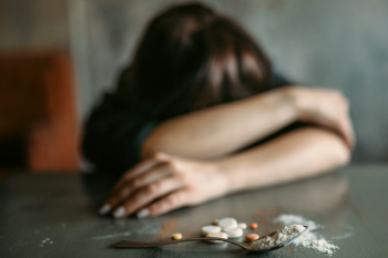 Женщина сидит за столом с наркотическими веществами